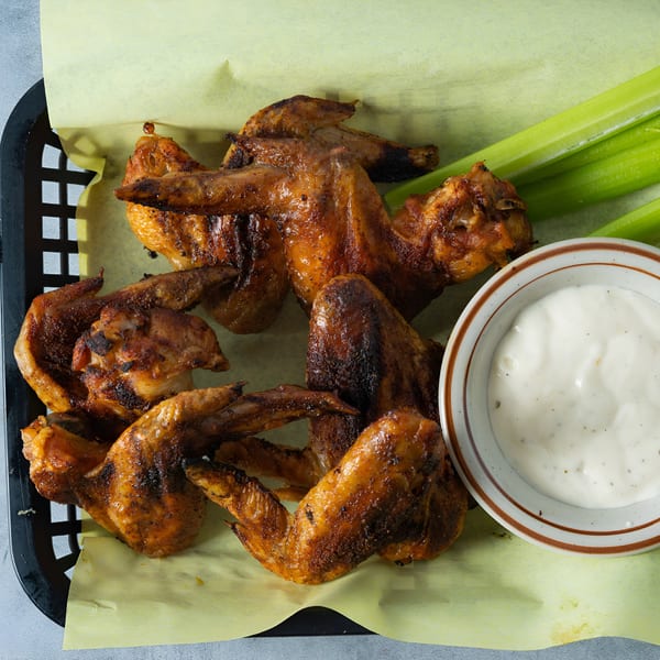Basket of Arizona BBQ Shack's grilled chicken wings with celery sticks and ranch dressing.