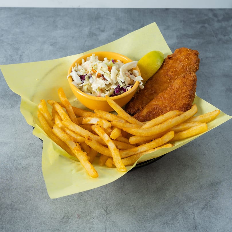 Golden-brown fried fish, french fries, and coleslaw in a yellow bowl, served in a basket.